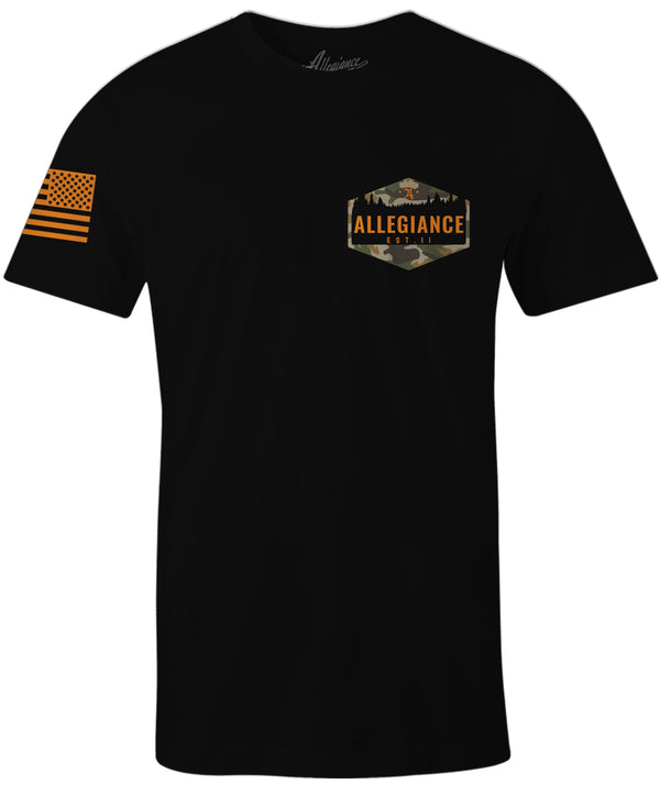 Front of Hunter Tee in black with small hexagonal forest silhouette graphic on the chest and American flag on the sleeve.