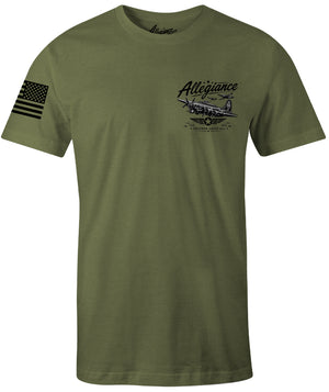 An olive green short-sleeve t-shirt with a black graphic on the left chest featuring a vintage airplane and the word 'Allegiance', plus a black American flag graphic on the right sleeve.
